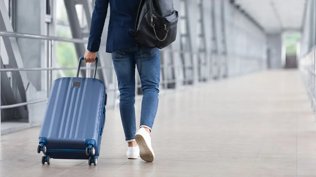 Ein Mann läuft mit einem Koffer zu einem Airport Terminal.