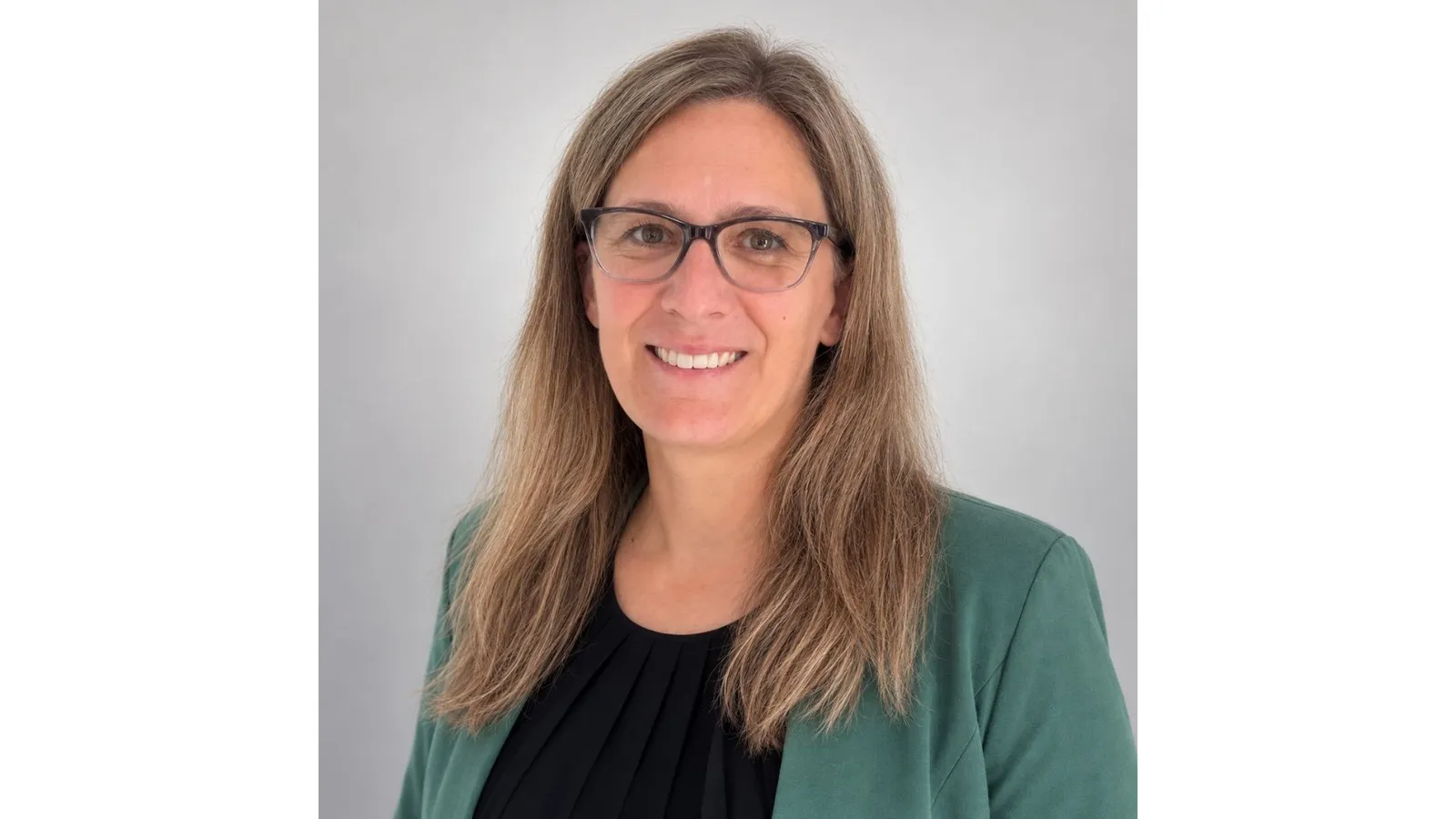 Nathalie Wilms lacht in die Kamera und trägt einen grünen Blazer.