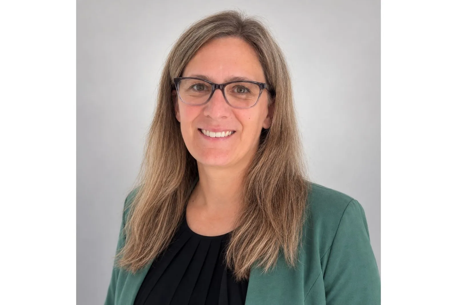 Nathalie Wilms lacht in die Kamera und trägt einen grünen Blazer.