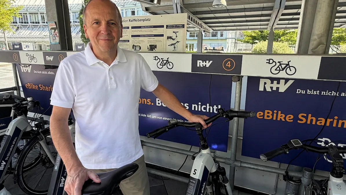 Hannes Davieds, Leiter Mobilitätsmanagement bei der R+V Versicherung an der unternehmenseigenen Fahrradstation, lächelt in die Kamera.