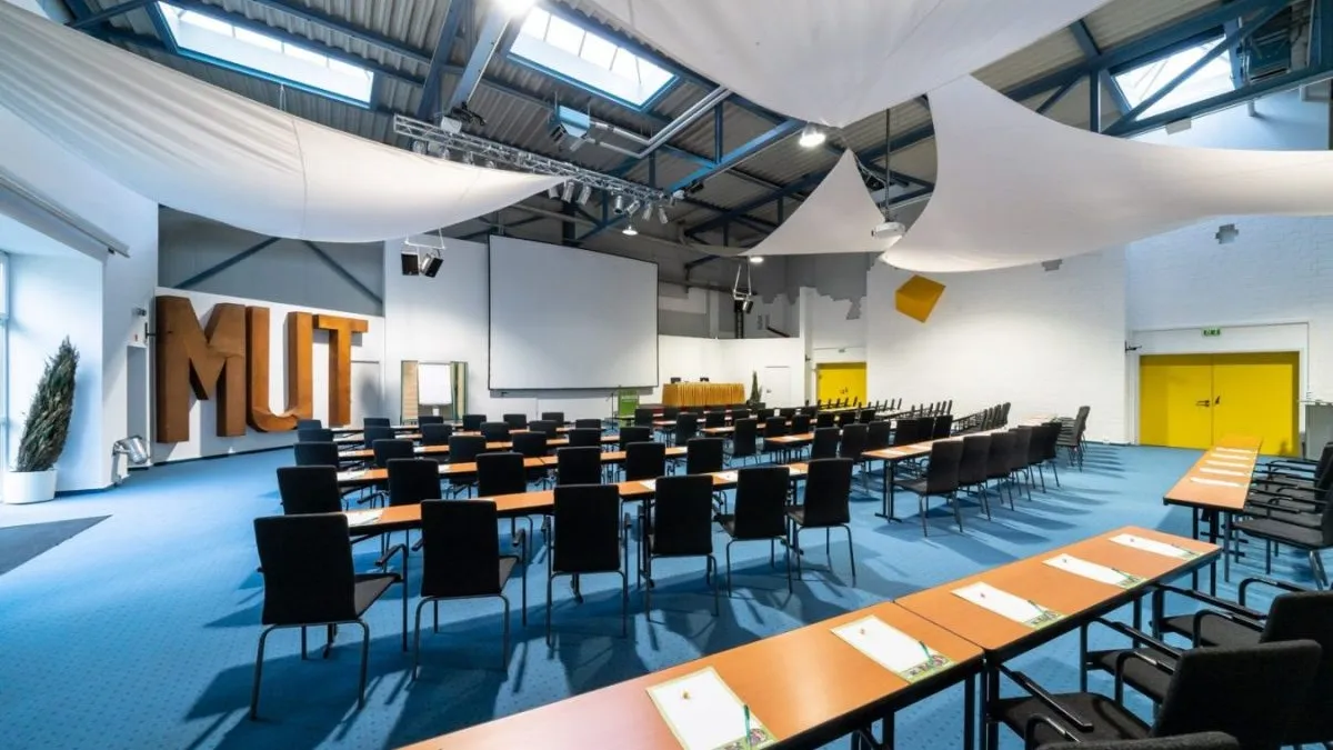 Im Tagungshotel Anders Walsrode stehen Tische und Stühle im bunten Konferenzraum.