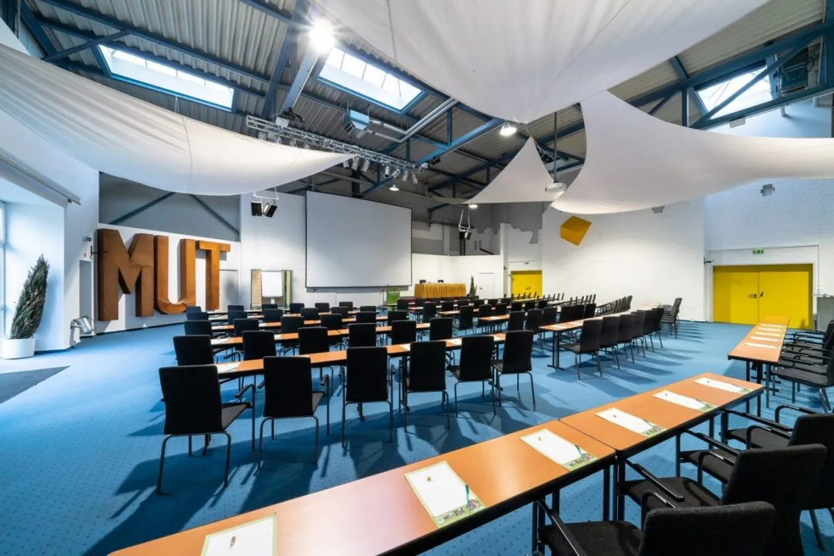 Im Tagungshotel Anders Walsrode stehen Tische und Stühle im bunten Konferenzraum.