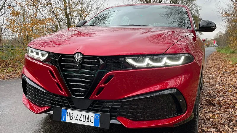 Front des roten Alfa Romeo Tonale mit neuem Kühlergrill und eingeschalteten LED-Scheinwerfern.