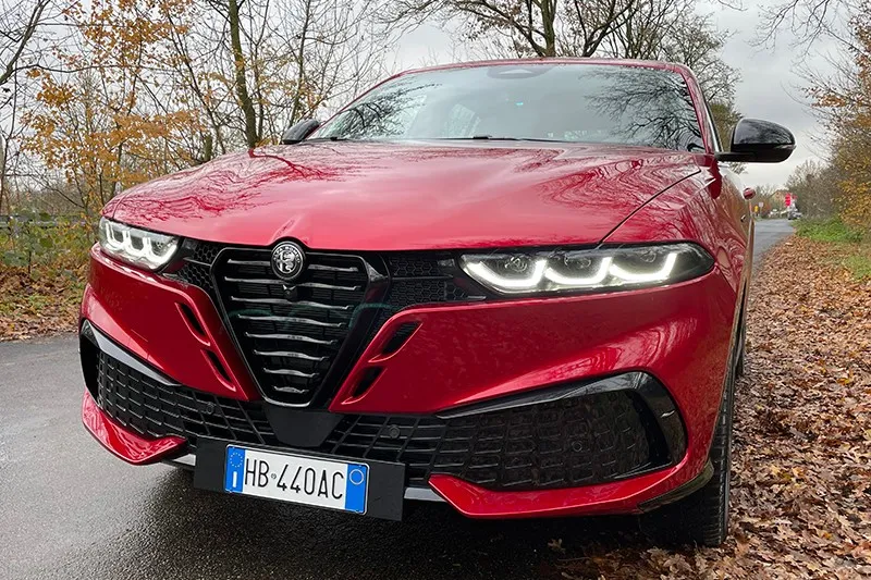 Front des roten Alfa Romeo Tonale mit neuem Kühlergrill und eingeschalteten LED-Scheinwerfern.