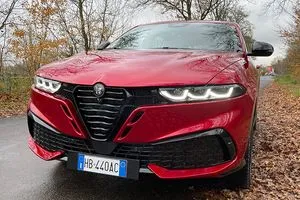 Front des roten Alfa Romeo Tonale mit neuem Kühlergrill und eingeschalteten LED-Scheinwerfern.