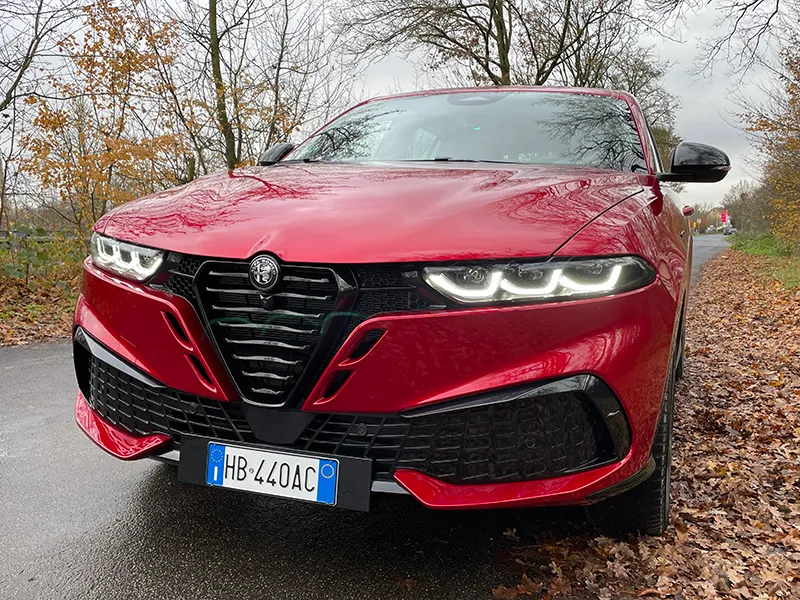 Front des roten Alfa Romeo Tonale mit neuem Kühlergrill und eingeschalteten LED-Scheinwerfern.