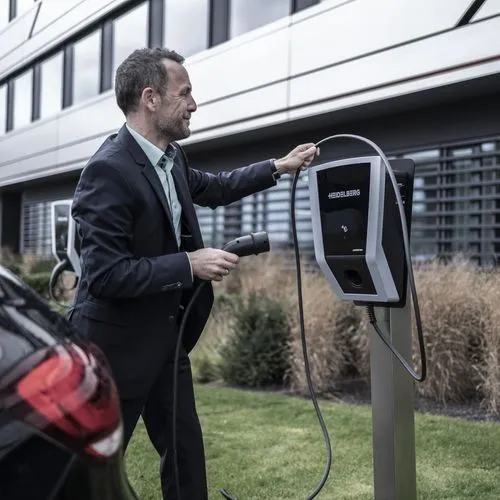 Ein Mann schließt ein Elektroauto an einer Ladesäule vor einem Firmengebäude an.