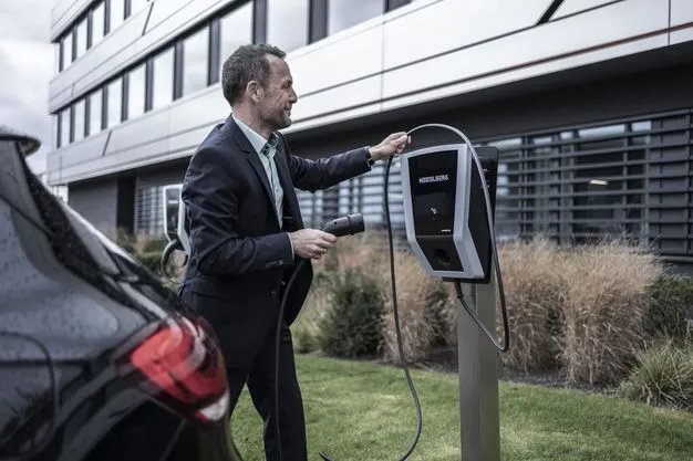 Ein Mann schließt ein Elektroauto an einer Ladesäule vor einem Firmengebäude an.