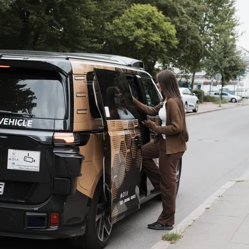 Autonomer VW ID. Buzz von Moia steht am Straßenrand, während eine Frau an der geöffneten Schiebetür einsteigt.