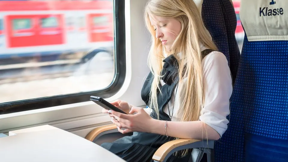 Blonde Frau sitzt in der ersten Klasse in einem Zug der Deutschen Bahn.