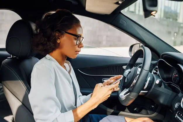 Frau im Auto tippt auf ihrem Handy.