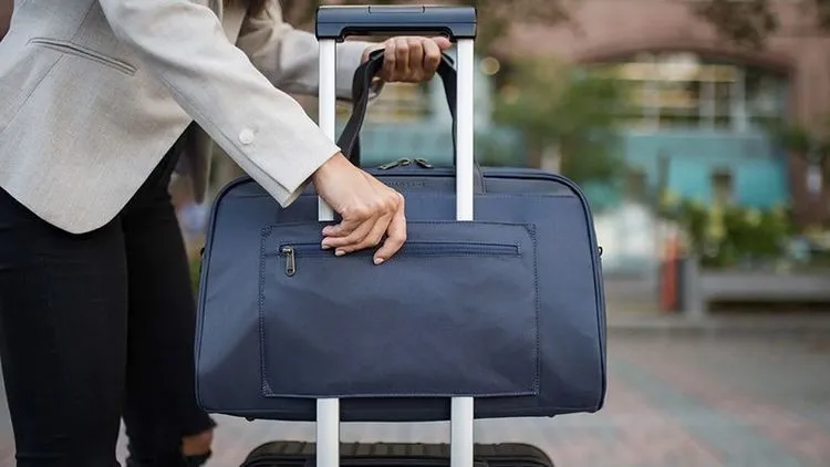 Handgepäck wird von Person auf dem Koffer abgestellt.