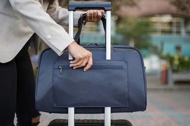 Handgepäck wird von Person auf dem Koffer abgestellt.