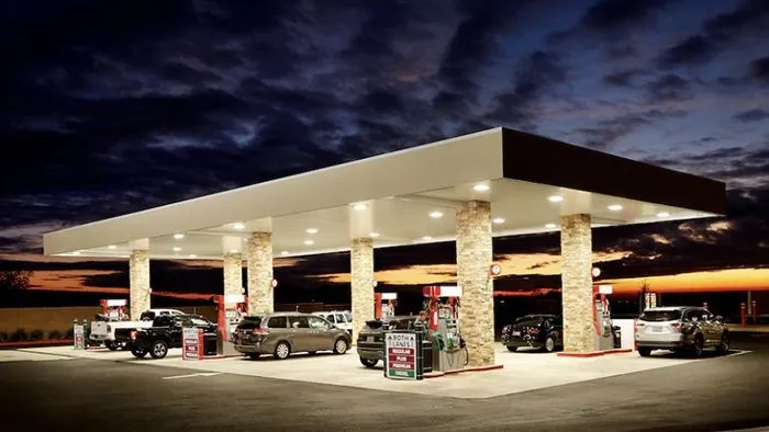 Beleuchtete Safeway-Tankstelle mit mehreren Fahrzeugen bei Sonnenuntergang.
