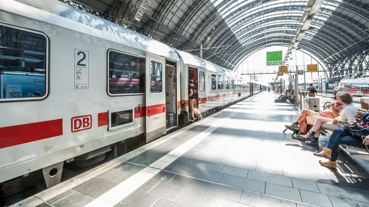 Ein Zug der Deutschen Bahn steht in einem Bahnhof und Leute steigen ein.