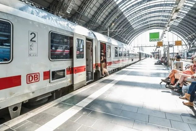Ein Zug der Deutschen Bahn steht in einem Bahnhof und Leute steigen ein.