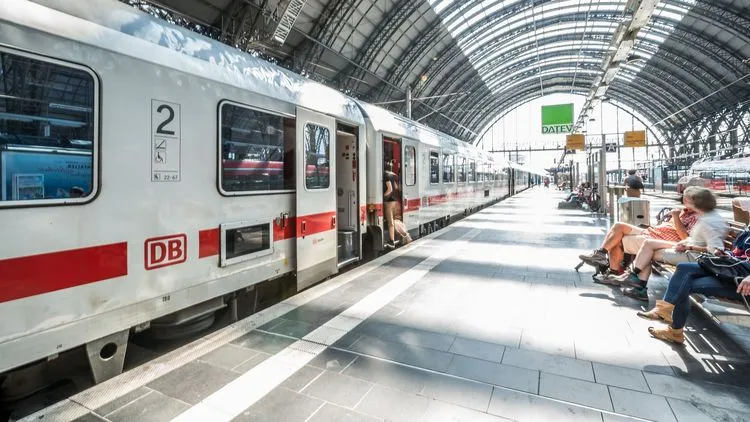 Ein Zug der Deutschen Bahn steht in einem Bahnhof und Leute steigen ein.