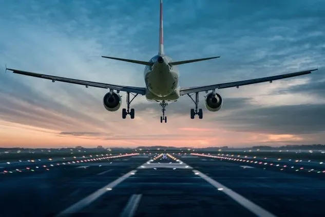 Ein Flugzeug fliegt im Sinkflug auf eine Landebahn zu.