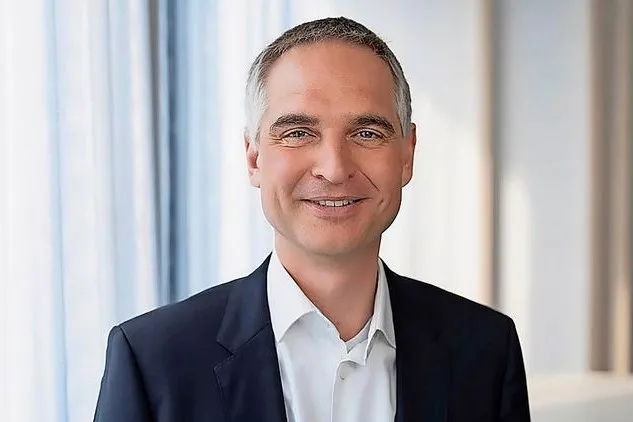 Steffen Krautwasser lächelt in Richtung Kamera und trägt einen Anzug.