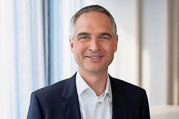 Steffen Krautwasser lächelt in Richtung Kamera und trägt einen Anzug.