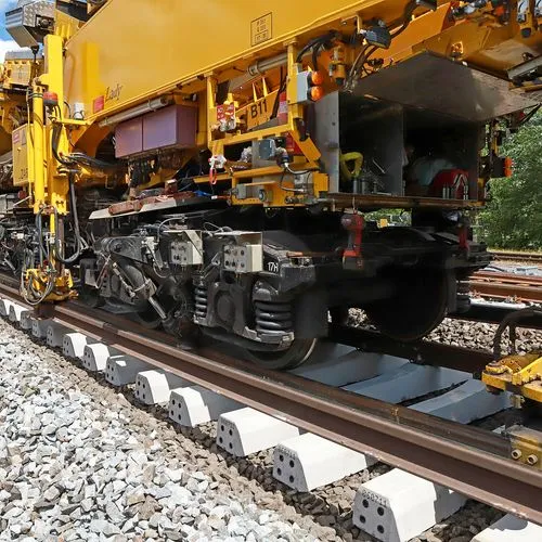 Gelbe Gleisbaumaschine bei Arbeiten an einer Bahnstrecke mit neu verlegten Betonschwellen und Schienen.
