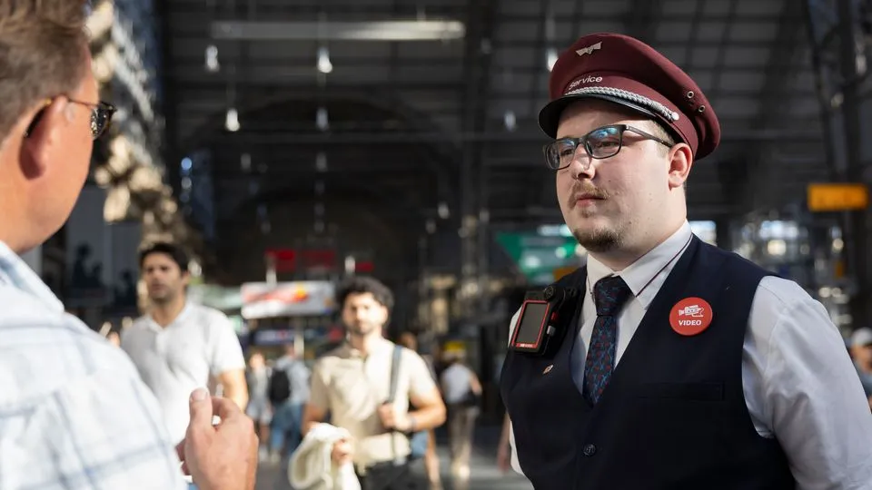 Mitarbeiter des Bahnhofsservice der DB mit Bodycam im Gespräch mit einem Reisenden am Hauptbahnhof Frankfurt (Main)