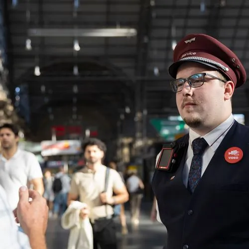 Mitarbeiter des Bahnhofsservice der DB mit Bodycam im Gespräch mit einem Reisenden am Hauptbahnhof Frankfurt (Main)