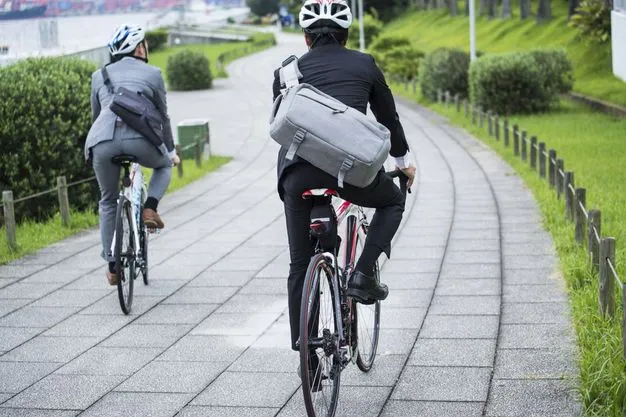 Zwei Männer im Anzug und mit Fahrradhelm und Umhängetasche auf dem Weg zur Arbeit auf dem Fahrrad