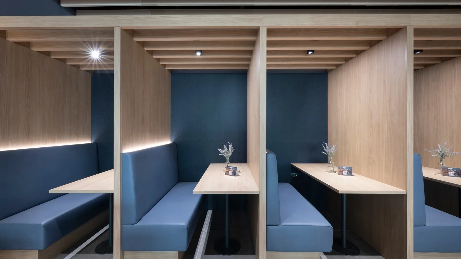 Von einer Holzwand abgetrennte Arbeitsplätze in der DUS Rhein Lounge.