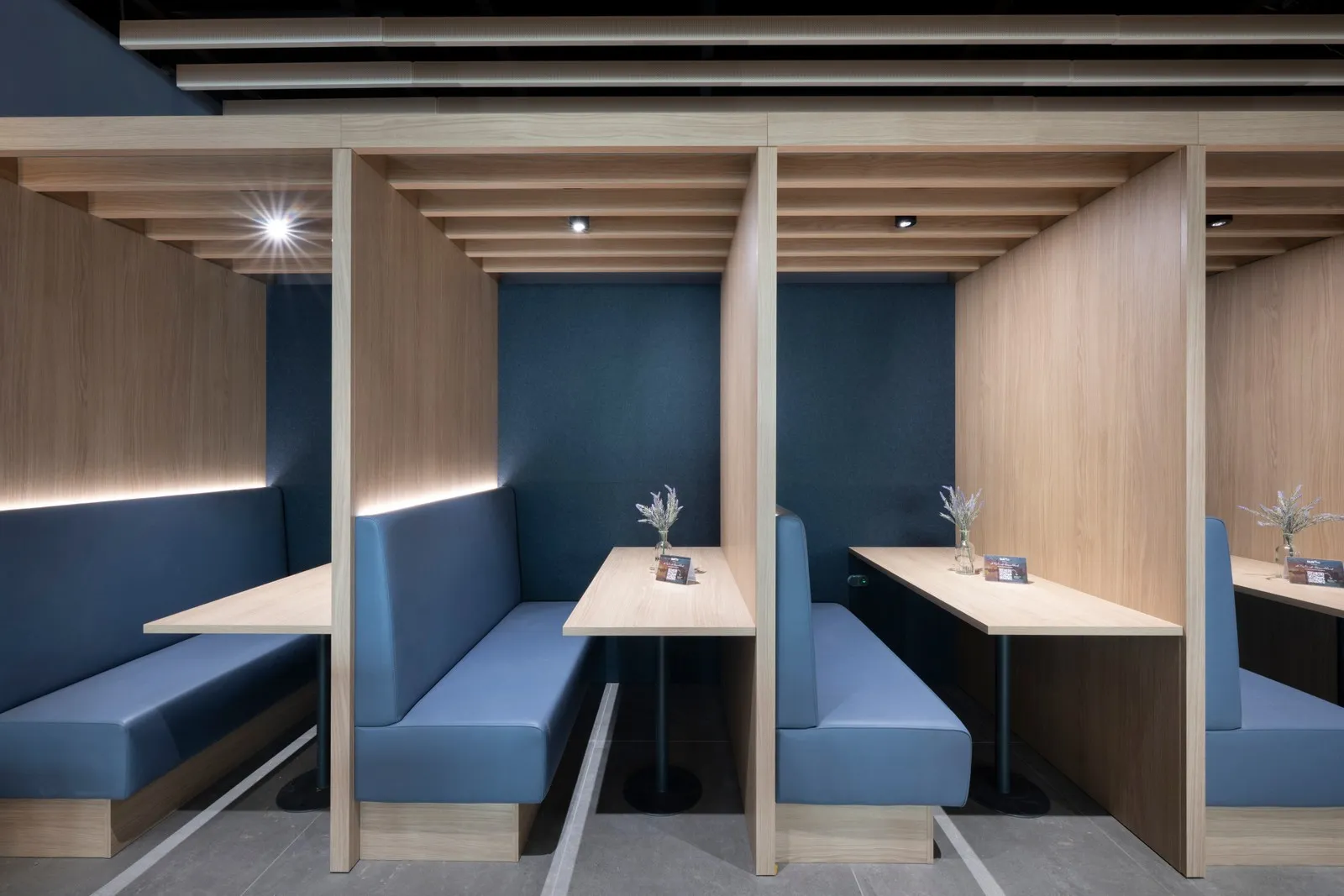 Von einer Holzwand abgetrennte Arbeitsplätze in der DUS Rhein Lounge.