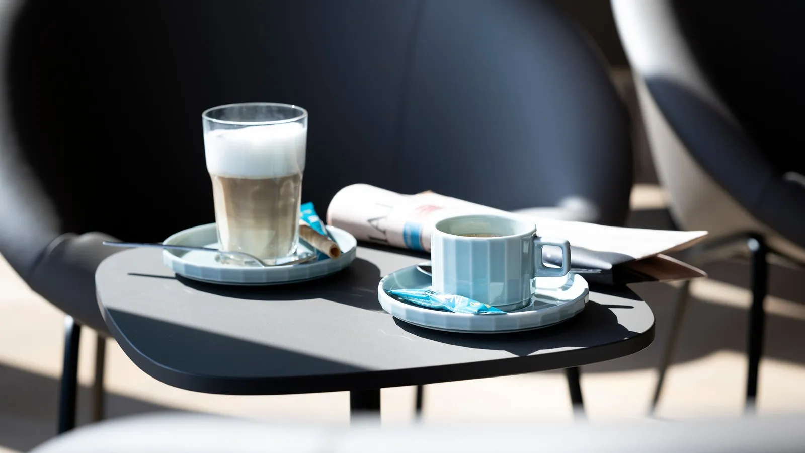 Latte Macchiato und Tee auf einem Tisch vor einem Ledersitz in der DUS Rhein Lounge.