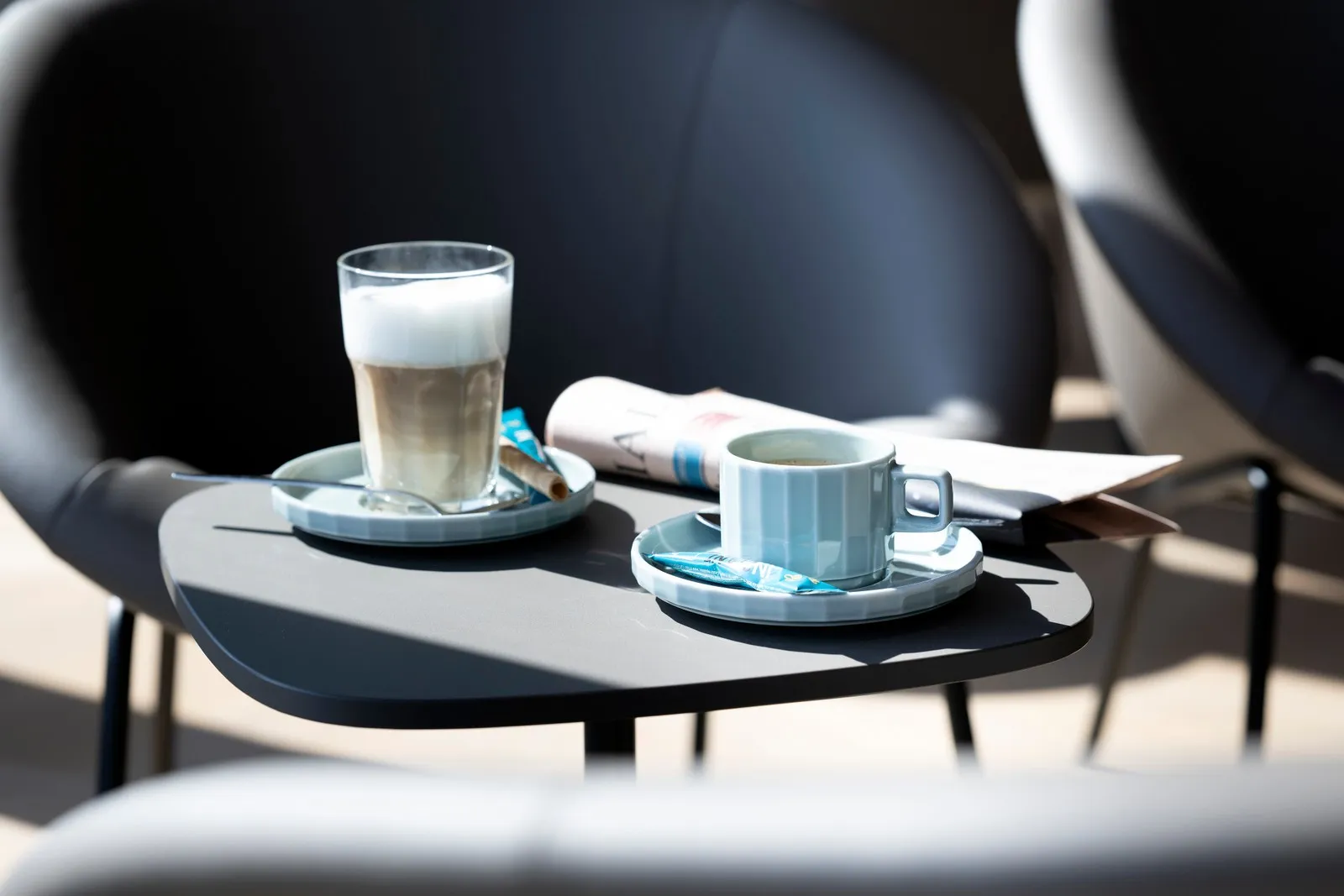 Latte Macchiato und Tee auf einem Tisch vor einem Ledersitz in der DUS Rhein Lounge.