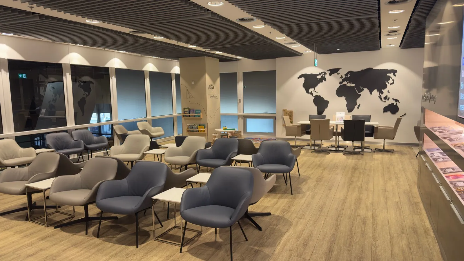 Sitzgelegenheiten und Gruppentische in der DUS Rhein Lounge, mit Zeitungen.