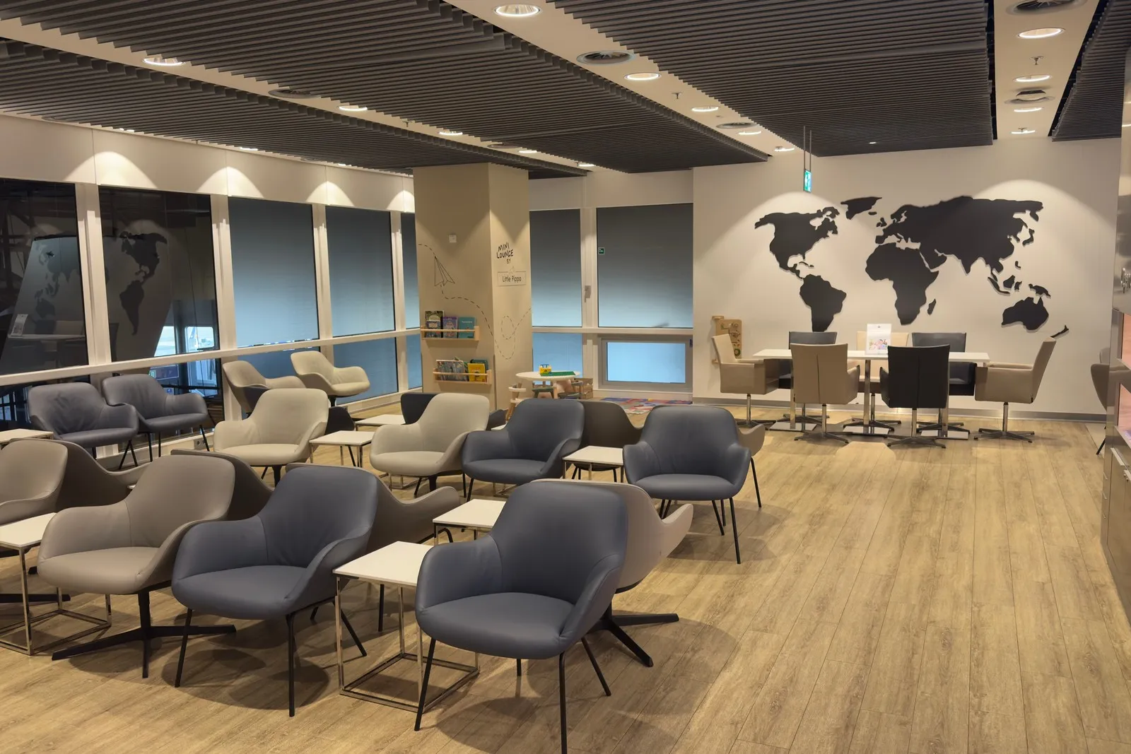 Sitzgelegenheiten und Gruppentische in der DUS Rhein Lounge, mit Zeitungen.