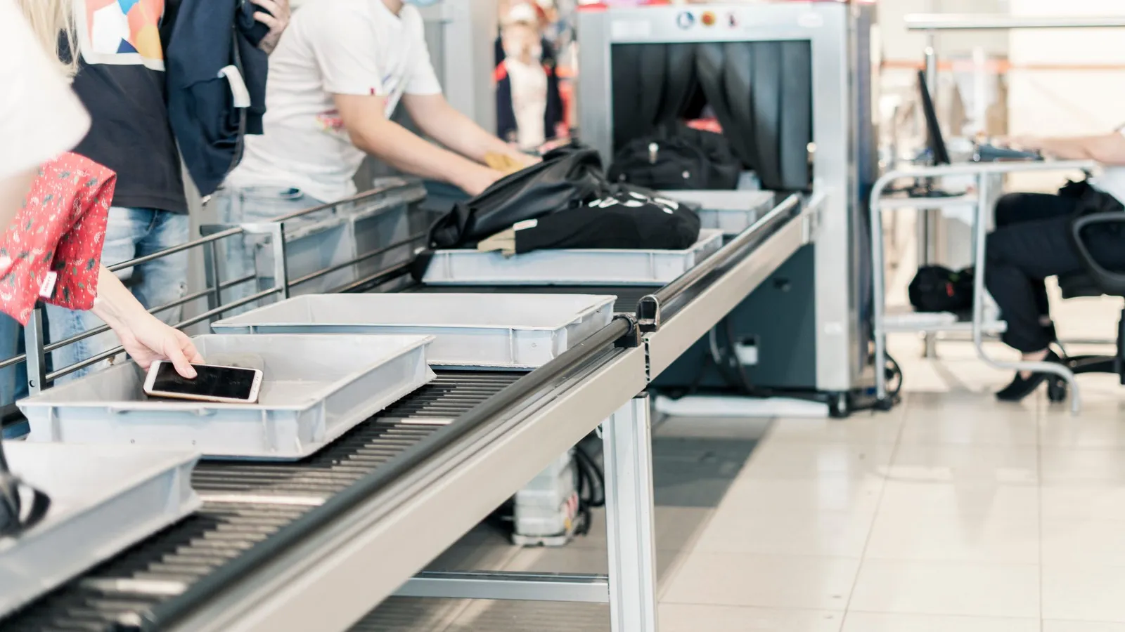 Menschen stehen an der Sicherheitskontrolle am Flughafen.
