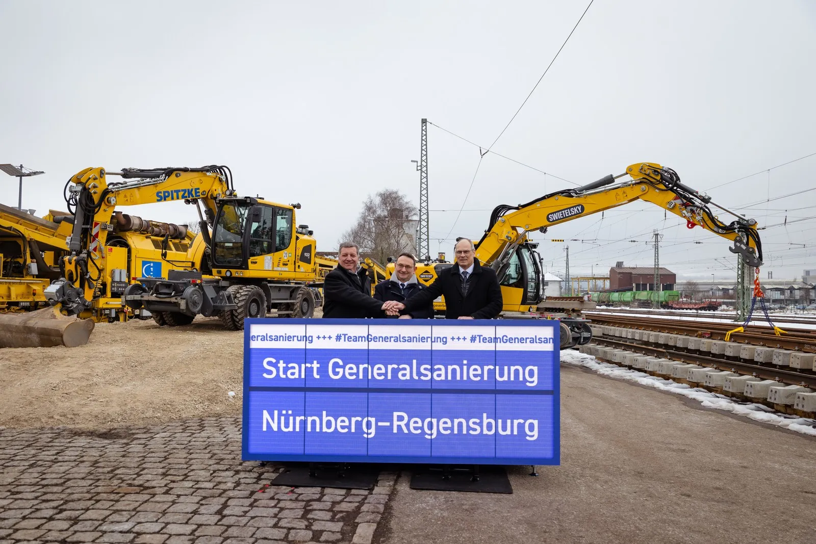 Die DB InfraGO beginnt mit der Generalsanierung der wichtigen Bahnstrecke Nürnberg – Regensburg. Gerd-Dietrich Bolte, Vorstand für Infrastrukturplanung und -projekte der DB InfraGO, der Parlamentarische Staatssekretär beim Bundesminister für Verkehr, Ulrich Lange, und der Bayerische Verkehrsminister Christian Bernreiter haben heute Mittag in Neumarkt (Oberpfalz) auf einer der rund 60 Baustelleneinrichtungsflächen das offizielle Startsignal gegeben.