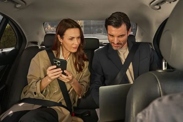Geschäftsreisende im Taxi mit Smartphone und Laptop