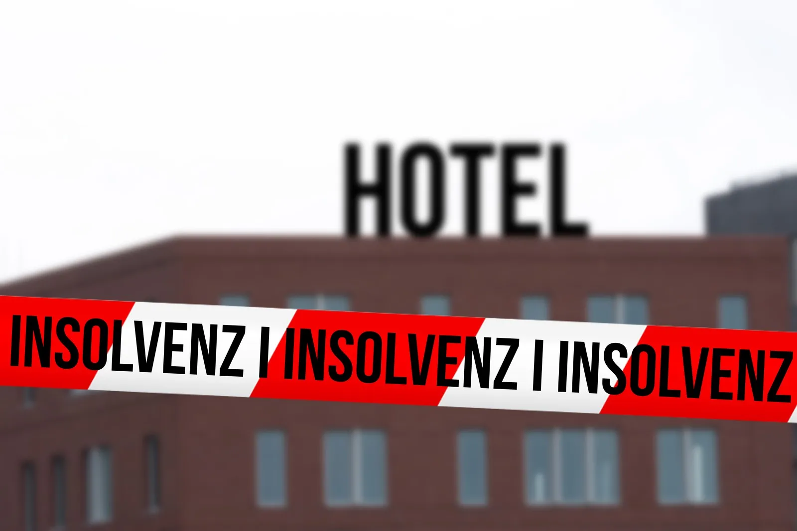 Hotel im Hintergrund und vorne ein rot-weißes Absperrband mit den Worten "Insolvenz".