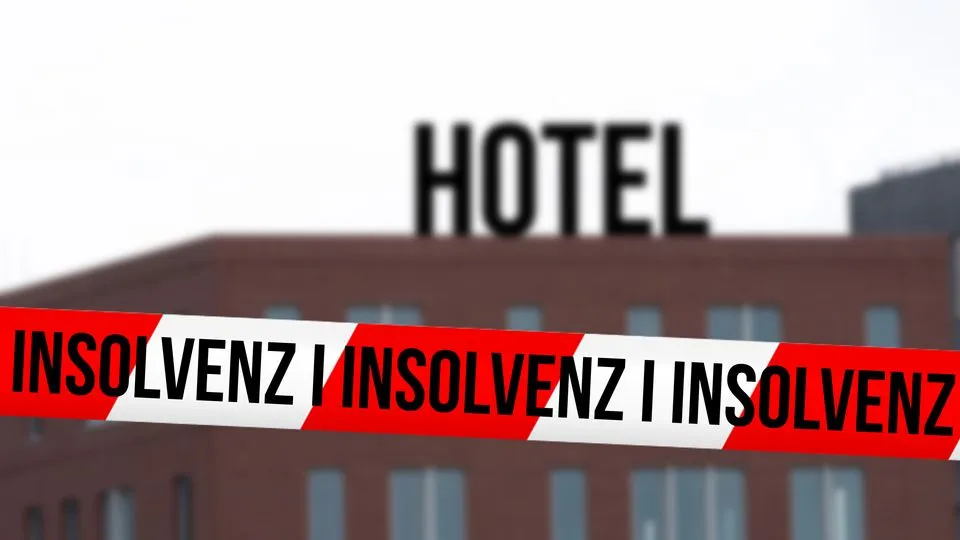 Hotel im Hintergrund und vorne ein rot-weißes Absperrband mit den Worten "Insolvenz".