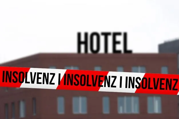 Hotel im Hintergrund und vorne ein rot-weißes Absperrband mit den Worten "Insolvenz".