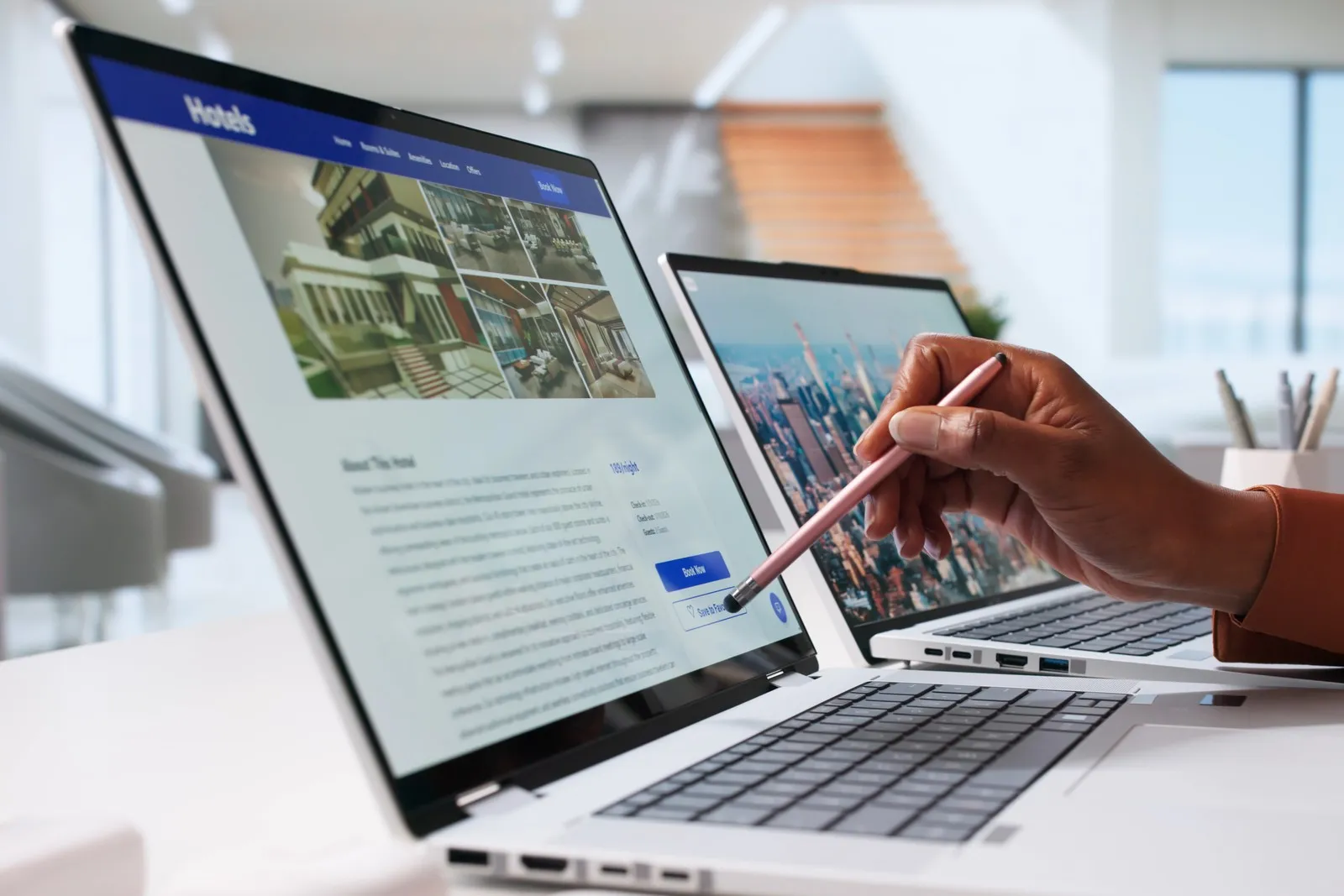 Eine Hand zeigt mit einem Stift auf einen Laptop. Auf dem Laptop ist eine Hotel-Buchungsseite geöffnet.