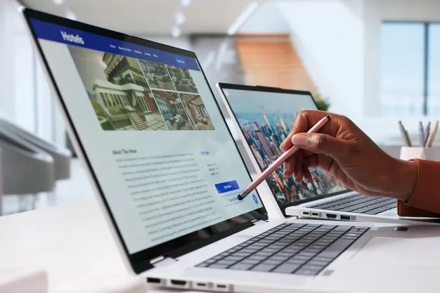Eine Hand zeigt mit einem Stift auf einen Laptop. Auf dem Laptop ist eine Hotel-Buchungsseite geöffnet.