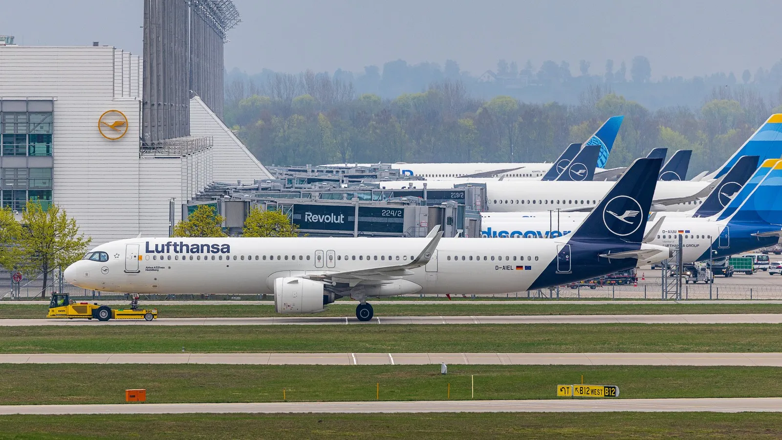 Ein Flugzeug der Lufthansa wird am Flughafen München mit einem Schlepper auf dem Vorfeld abgestellt.