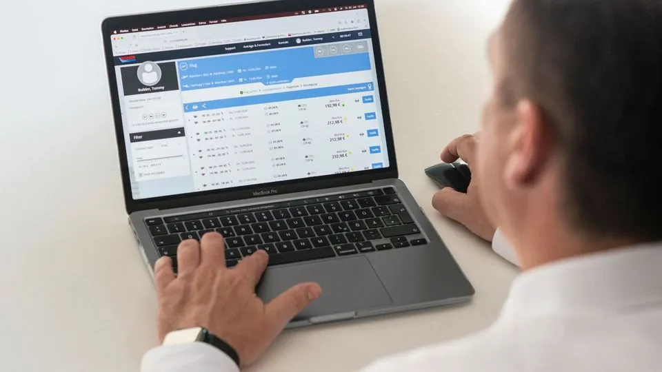 Mann nutzt am Laptop ein digitales Buchungstool für Flugreisen.
