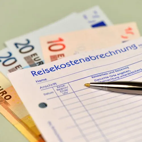 Ein Zettel der Reisekostenabrechnung liegt auf Geldscheinen.