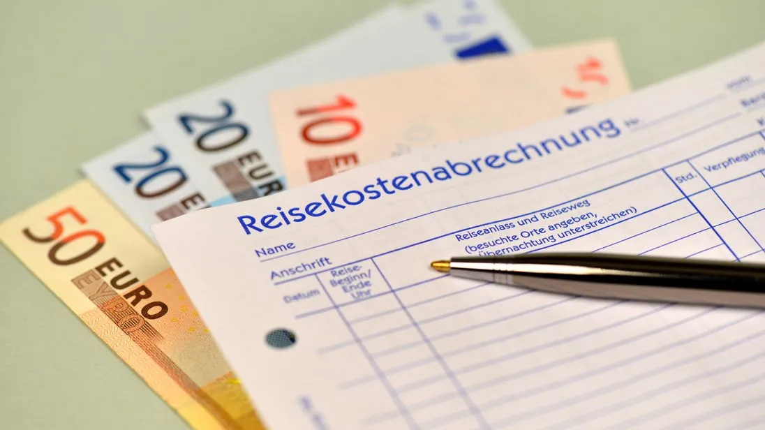 Ein Zettel der Reisekostenabrechnung liegt auf Geldscheinen.