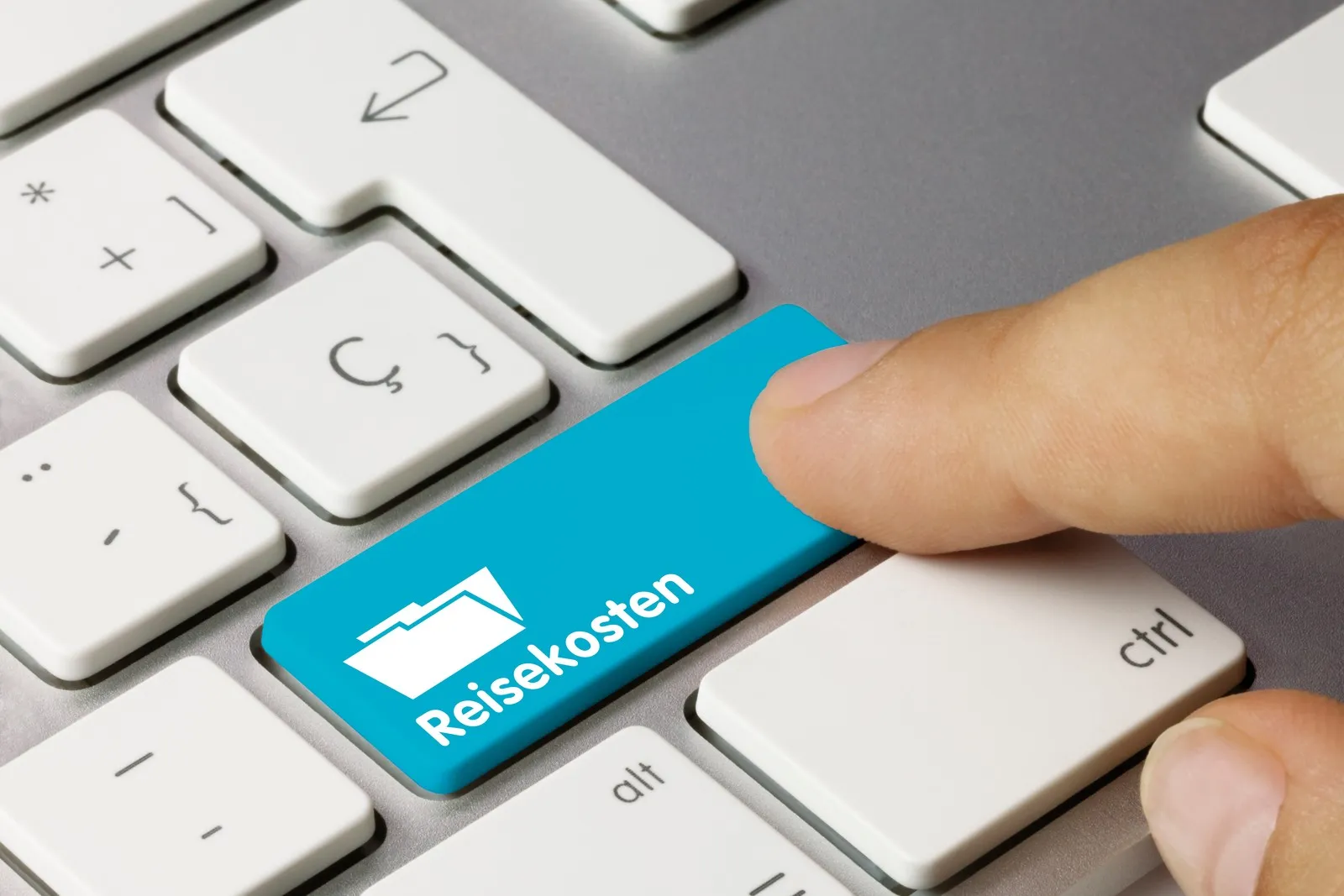 Finger drückt auf einer Computertastatur eine blaue Taste mit der Aufschrift „Reisekosten“.