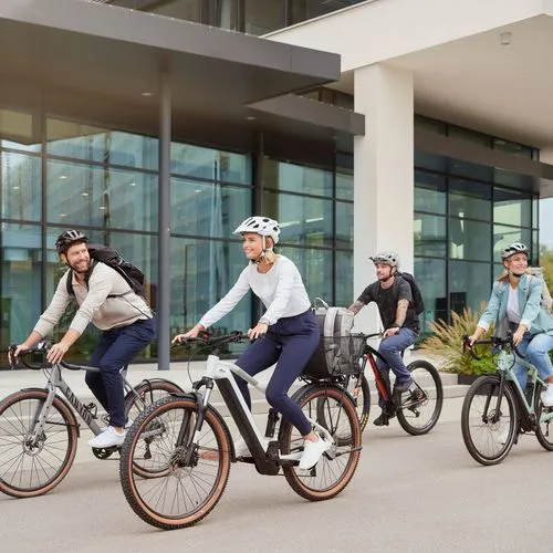 Vier Menschen fahren auf Fahrrädern an einem Gebäude mit Glasscheiben vorbei.
